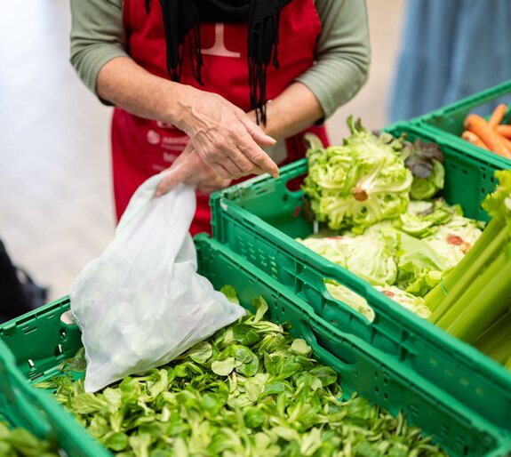 Freiwillige Helferin verpackt an einer Abgabestelle der Hilfsorganisation Tischlein deck dich gerettete Lebensmittel für armutsbetroffene Menschen in der Schweiz.