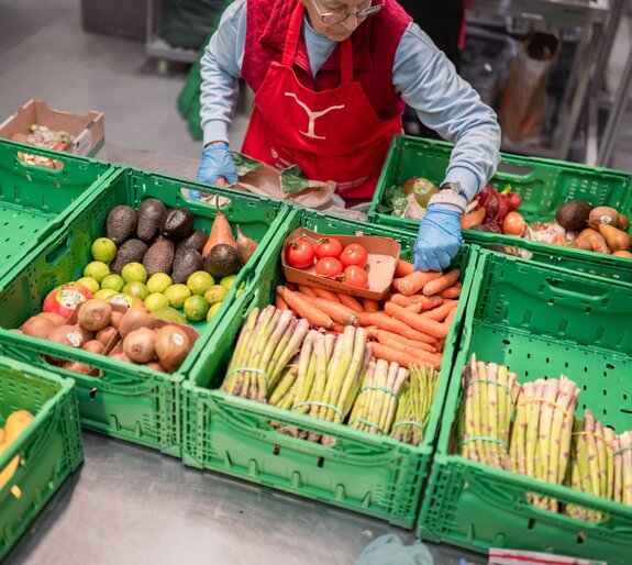 Freiwillige Helferin der Hilfsorganisation Tischlein deck dich stellt am Logistik-Standort Staufen gerettete Lebensmittel für die Lebensmittelabgabe an Armutsbetroffene Menschen zusammen.