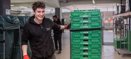 Zivildienstleistender zieht Paletten durch ein Logistiklager der Hilfsorganisation Tischlein deck dich.