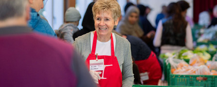 Freiwillige Helferinnen und Helfer verteilen an einer Abgabestelle der national tätigen Hilfsorganisation Tischlein deck dich gerettete Lebensmittel an armutsbetroffene Menschen.